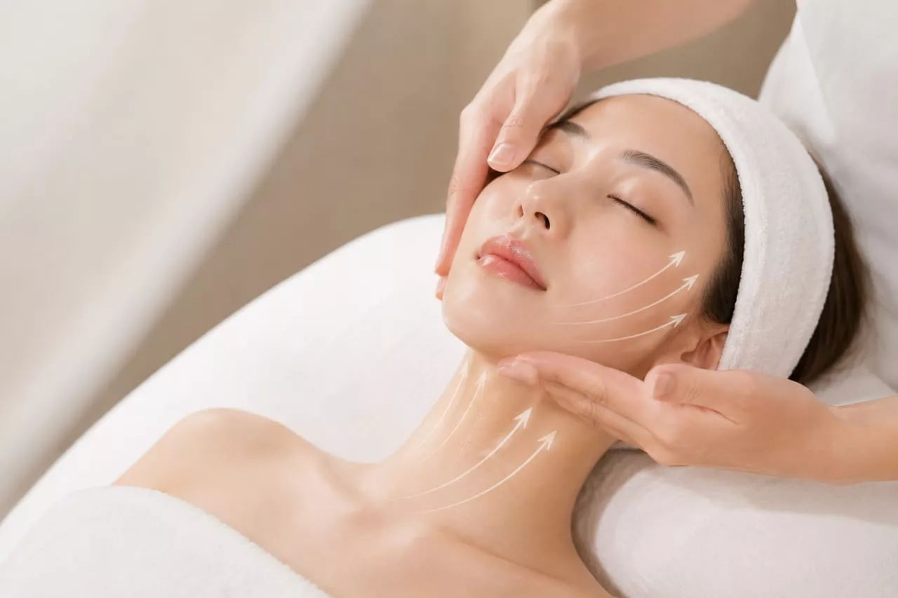A therapist's hands sculpting along the jawline and neck during a Fascia Sculpt Lift treatment.